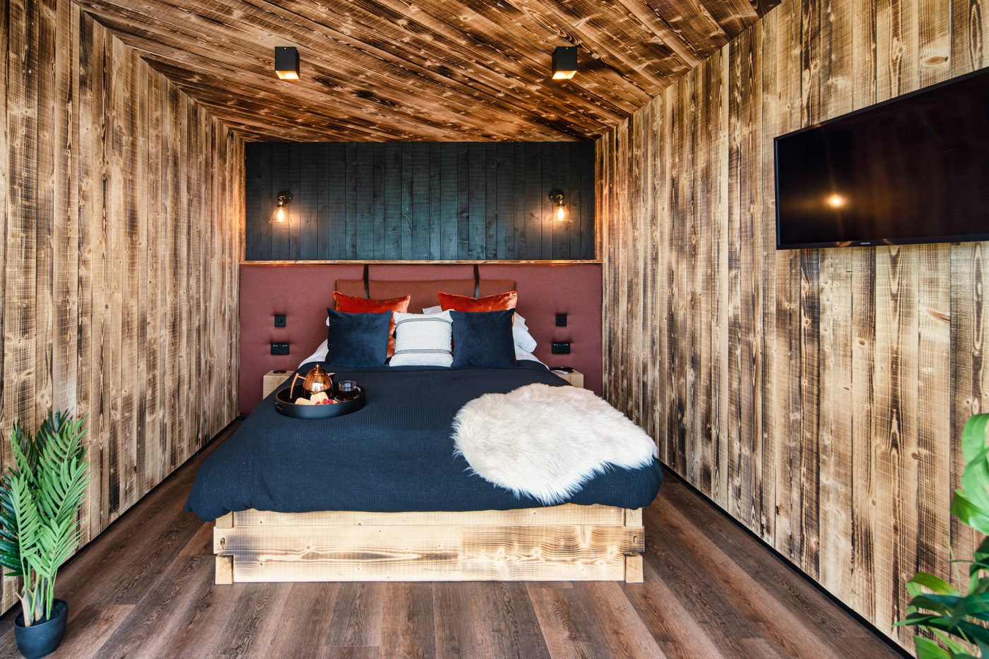 The Rusty Boathouse bedroom facing the bed — dark timber panelling and flatscreen TV