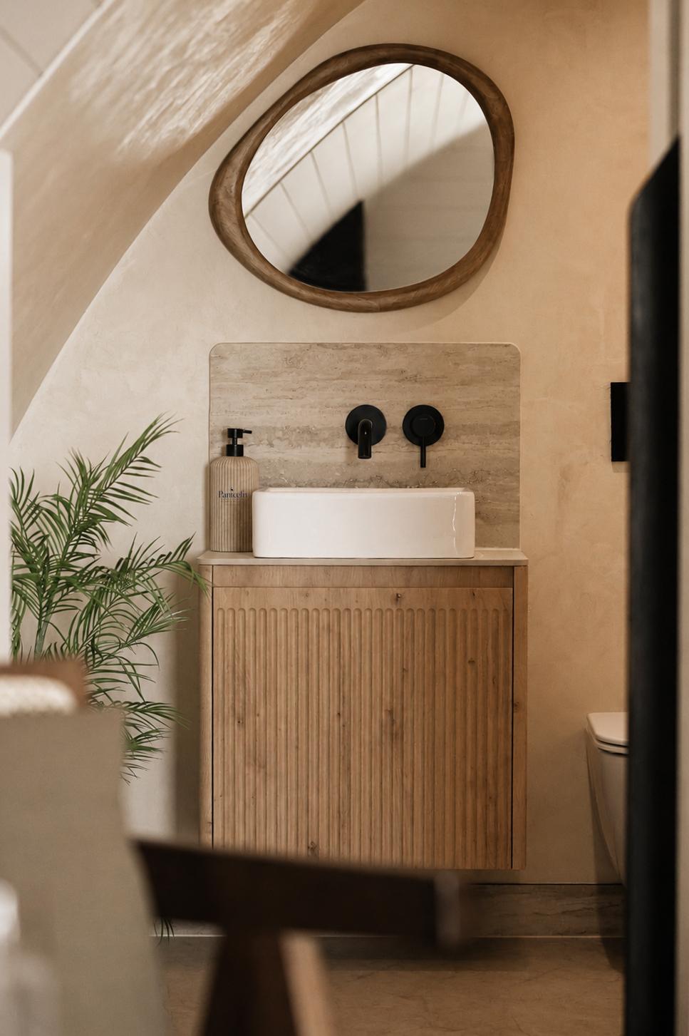 Bathroom vanity with oval mirror and travertine splashback