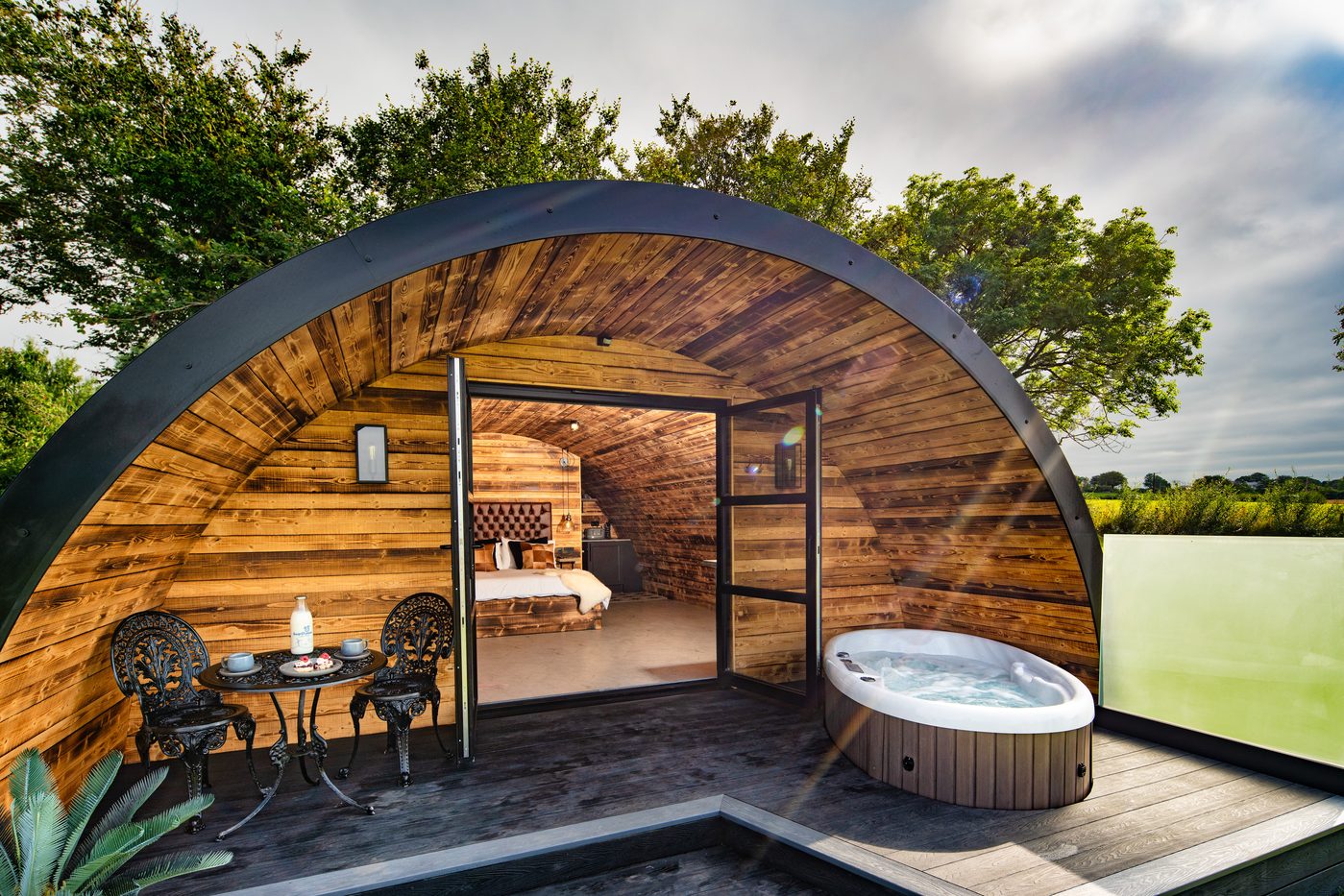 The Piglet Pod exterior in daylight — arch open to hot tub and countryside