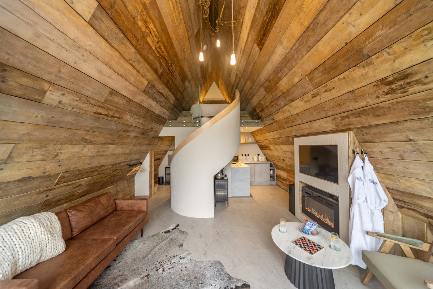 Sculptural white spiral staircase inside the Tri-Pod leading to the mezzanine bedroom