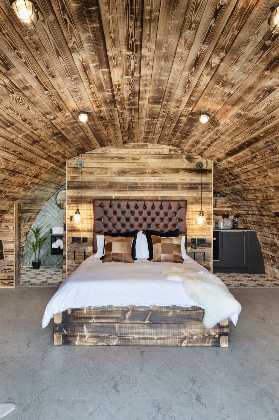The Piglet Pod interior — king-size bed under the curved timber arch