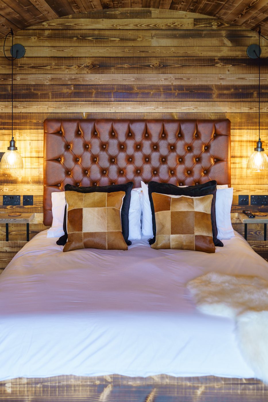 Close up of the buttoned cognac leather headboard with pendant lights