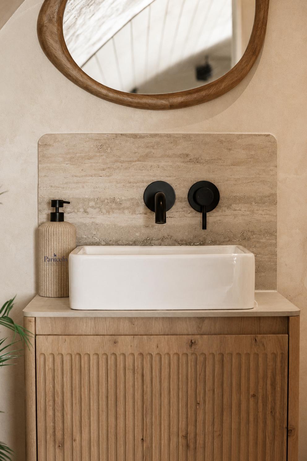 Close-up of the vessel sink, black taps and travertine backsplash