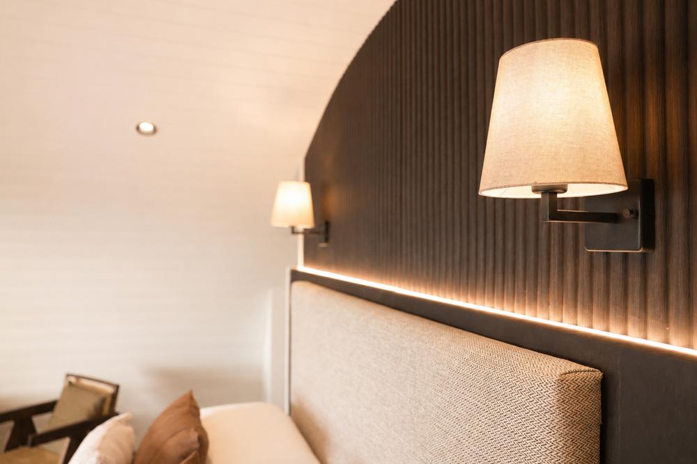Wall sconces either side of the bed's dark timber headboard