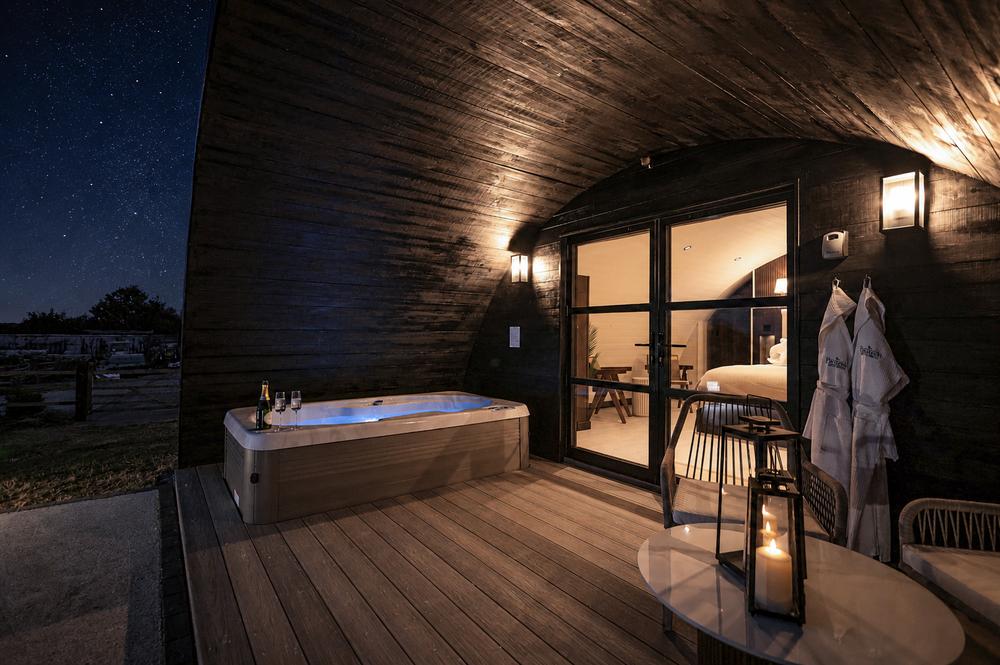 The hot tub glowing after dark, with the bedroom lit up beyond