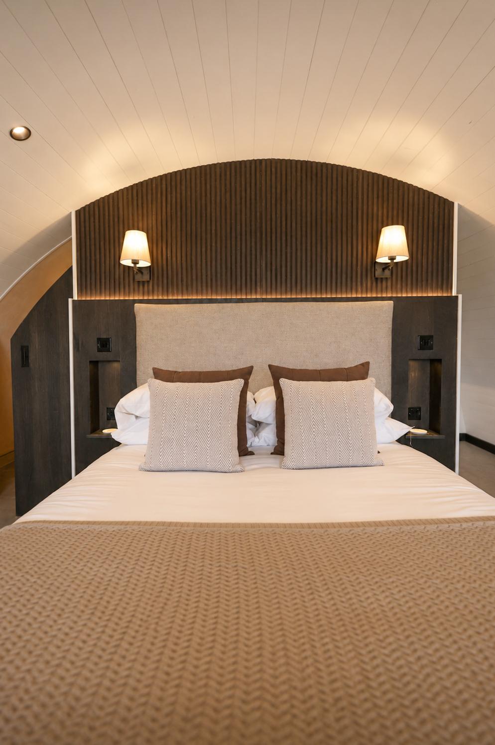Close-up of the king-size bed's wood-panelled headboard and wall sconces