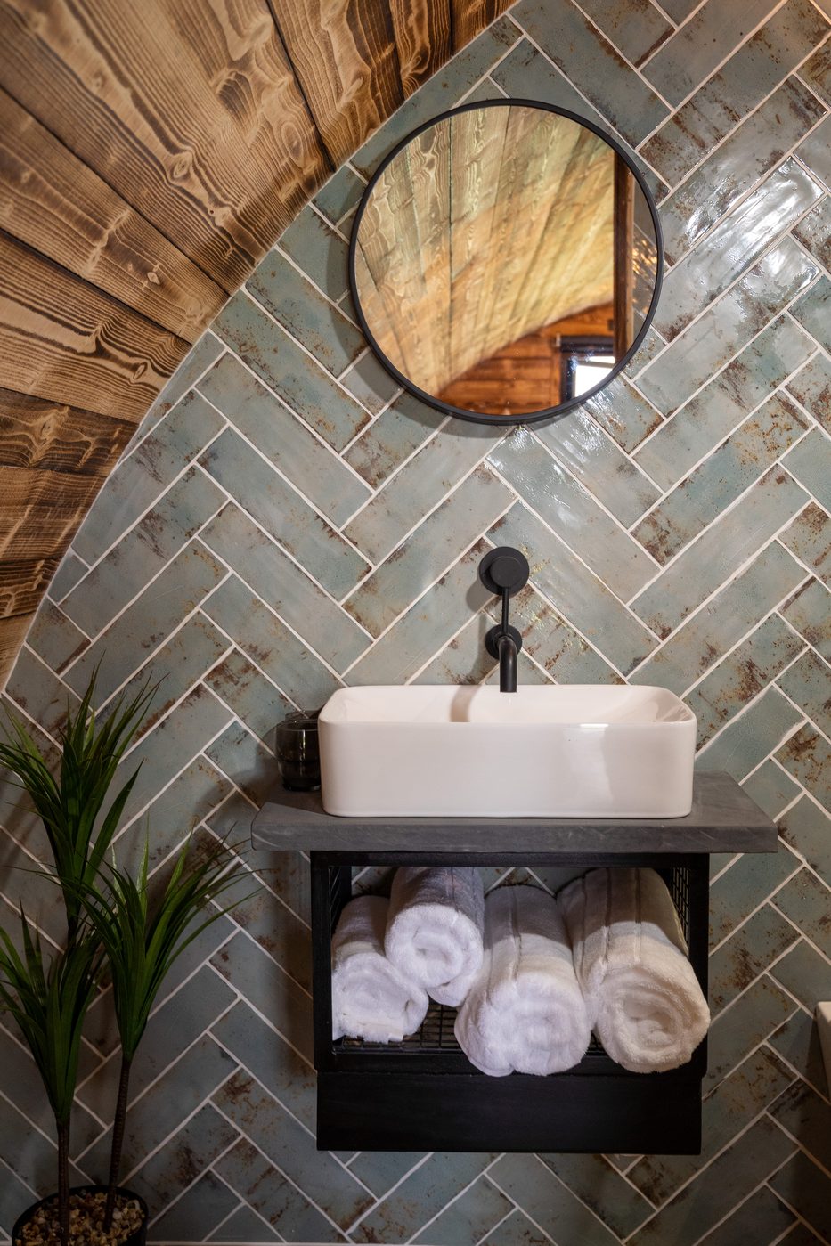 Bathroom vanity — white vessel sink, round mirror and rolled towels