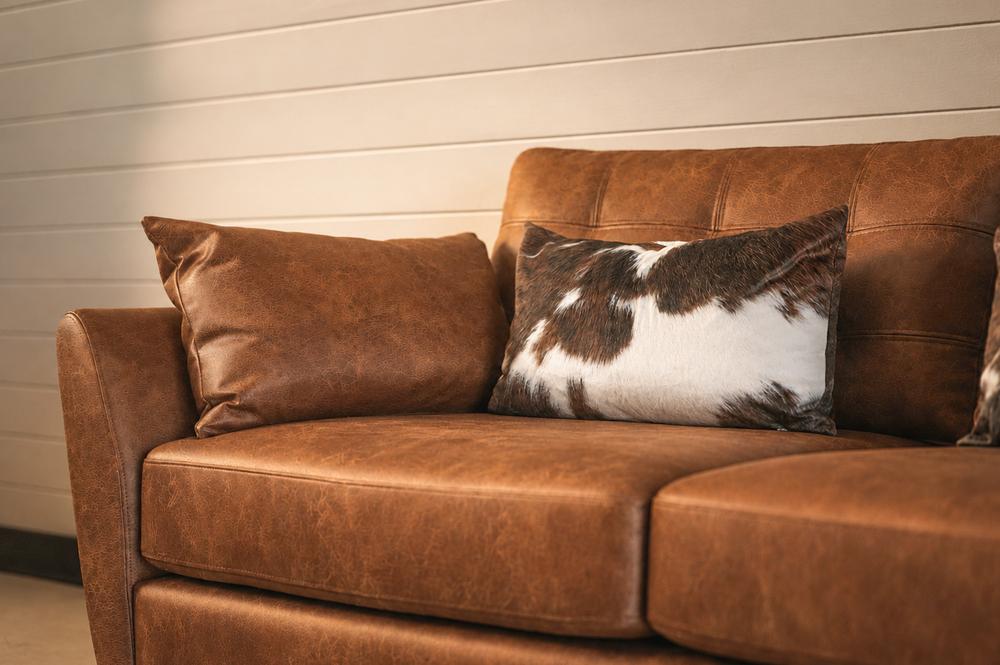 Detail of the tan leather sofa with a cowhide-print cushion